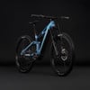 Ein blaues E-Mountainbike mit Federung und schwarzen Rädern vor dunklem Hintergrund.