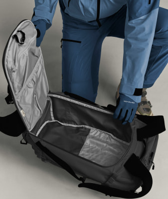 Eine Person in blauer Kleidung betrachtet das Innere einer grauen Tasche. Eine Person in blauer Kleidung betrachtet das Innere einer grauen Tasche.