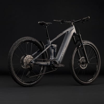 Graues Cube E-Bike mit Federung und schwarzen Rädern auf dunklem Hintergrund. Graues Cube E-Bike mit Federung und schwarzen Rädern auf dunklem Hintergrund.
