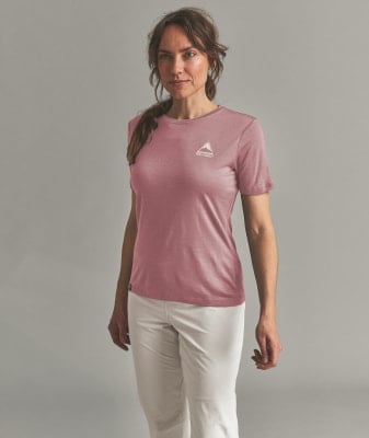 Eine Frau in einem rosa T-Shirt und hellen Hosen posiert vor einem grauen Hintergrund. Eine Frau in einem rosa T-Shirt und hellen Hosen posiert vor einem grauen Hintergrund.