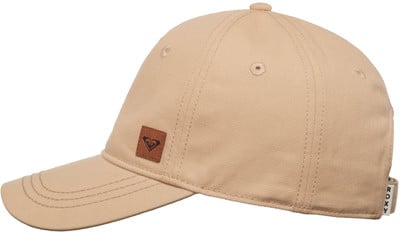 Eine beige Kappe mit braunem Lederetikett und Roxy-Logo. Eine beige Kappe mit braunem Lederetikett und Roxy-Logo.