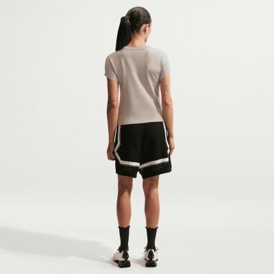 Eine Frau in einem grauen T-Shirt und schwarzen Shorts mit weißen Streifen steht rückwärts. Eine Frau in einem grauen T-Shirt und schwarzen Shorts mit weißen Streifen steht rückwärts.