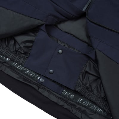 Detail der Innenseite einer dunkelblauen Jacke mit Druckknöpfen und Logo. Detail der Innenseite einer dunkelblauen Jacke mit Druckknöpfen und Logo.