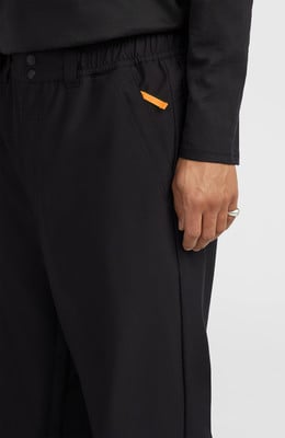 Detail einer schwarzen Hose mit orangefarbenem Detail und einem Ring am Finger. Detail einer schwarzen Hose mit orangefarbenem Detail und einem Ring am Finger.