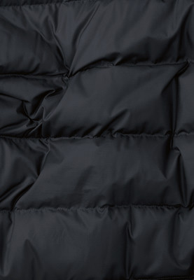 Detail einer gesteppten schwarzen Jacke mit sichtbarer Stofftextur. Detail einer gesteppten schwarzen Jacke mit sichtbarer Stofftextur.