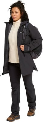 Eine Frau in einem schwarzen Mantel, einem weißen Fleece und schwarzen Hosen mit Rucksack. Eine Frau in einem schwarzen Mantel, einem weißen Fleece und schwarzen Hosen mit Rucksack.