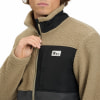 Mann in einem beigefarbenen Fleece-Reißverschluss mit schwarzen Einsätzen.