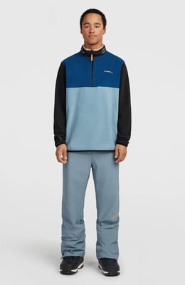 Ein Mann in einem blauen Fleece-Pullover und grauer Hose posiert vor hellem Hintergrund. Ein Mann in einem blauen Fleece-Pullover und grauer Hose posiert vor hellem Hintergrund.