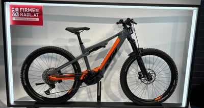 Ein KTM E-Mountainbike in Grau und Orange mit Beschriftung auf dem Rahmen. Ein KTM E-Mountainbike in Grau und Orange mit Beschriftung auf dem Rahmen.