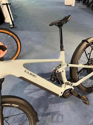 Graues Cube E-Bike mit Federung und Geländereifen auf blauem Teppich.