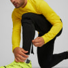 Ein Mann schließt den Reißverschluss an schwarzen Sporthosen, er trägt ein gelbes Sweatshirt.