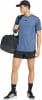 Ein Mann in einem blauen T-Shirt und schwarzen Shorts trägt eine Tasche über der Schulter.