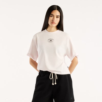 Eine Frau in einem rosa T-Shirt und schwarzen Shorts mit Logo auf der Brust.
