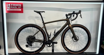 Ein braunes Gravelbike mit schwarzen Felgen und braunen Reifen steht auf einem Ständer.