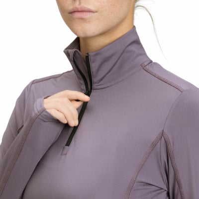Eine Frau schließt einen lila Pullover mit Reißverschluss am Hals. Eine Frau schließt einen lila Pullover mit Reißverschluss am Hals.