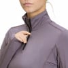 Eine Frau schließt einen lila Pullover mit Reißverschluss am Hals.