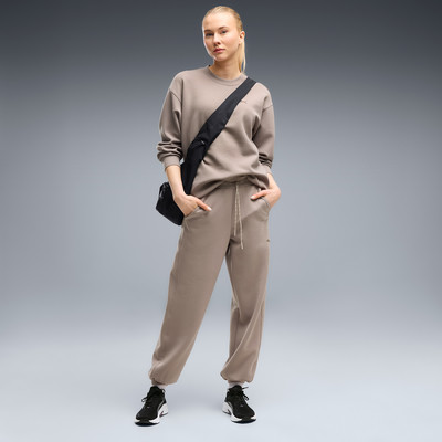Frau in beiger Jogginghose und Pullover mit schwarzer Umhängetasche. Frau in beiger Jogginghose und Pullover mit schwarzer Umhängetasche.