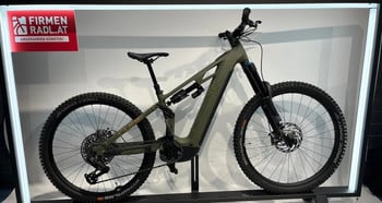 Ein grünes Cube E-Bike steht neben einer roten Werbung im Ausstellungsstand.