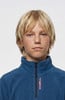 Ein Junge mit blonden Haaren und Sommersprossen auf dem Gesicht trägt einen blauen Fleece-Pullover.