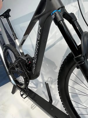 Ein schwarzes Mondraker E-Mountainbike mit Federung und Reifen auf einem Ständer. Ein schwarzes Mondraker E-Mountainbike mit Federung und Reifen auf einem Ständer.
