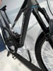 Ein schwarzes Mondraker E-Mountainbike mit Federung und Reifen auf einem Ständer.