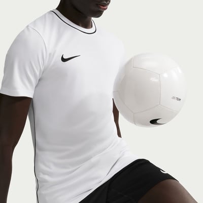 Ein Mann im weißen Nike-Trikot mit schwarzer Paspel hält einen weißen Fußball. Ein Mann im weißen Nike-Trikot mit schwarzer Paspel hält einen weißen Fußball.