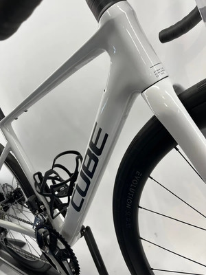 Ein weißes Rennrad der Marke CUBE mit schwarzer Schrift auf dem Rahmen. Ein weißes Rennrad der Marke CUBE mit schwarzer Schrift auf dem Rahmen.