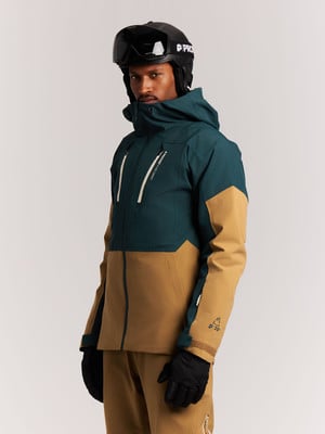 Ein Mann in einer Skijacke und einem Helm mit Brille blickt in die Kamera. Ein Mann in einer Skijacke und einem Helm mit Brille blickt in die Kamera.