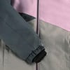 Ärmeldetail einer Jacke mit Farbblockierung und schwarzem Bündchen.