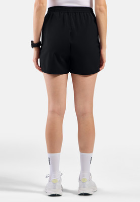 Eine Frau in schwarzen Shorts und weißen Socken steht mit dem Rücken zur Kamera.