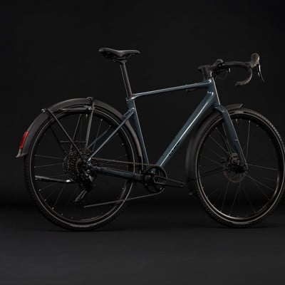 Ein dunkelgraues Fahrrad mit Schutzblechen und Gepäckträger vor schwarzem Hintergrund. Ein dunkelgraues Fahrrad mit Schutzblechen und Gepäckträger vor schwarzem Hintergrund.