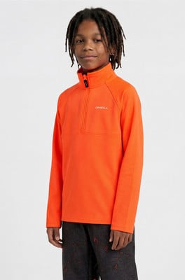 Junge in einem orangefarbenen Fleece-Pullover mit O'Neill-Logo und schwarzer Hose. Junge in einem orangefarbenen Fleece-Pullover mit O'Neill-Logo und schwarzer Hose.