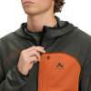 Mann schließt dunkle Kapuzenjacke mit orangefarbenem Einsatz und McKinley-Logo.