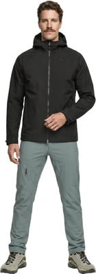 Ein Mann in schwarzer Kapuzenjacke und grauer Hose steht. Ein Mann in schwarzer Kapuzenjacke und grauer Hose steht.