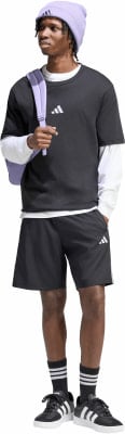 Junger Mann in schwarzem T-Shirt, Shorts und lila Mütze