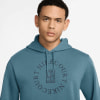 Ein Mann in einem blauen Kapuzenpullover mit Nike Court-Logo und einem Tennisplatz.