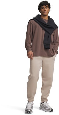 Ein Mann in einem braunen Langarmshirt mit schwarzem Pullover über den Schultern, beige Hose. Ein Mann in einem braunen Langarmshirt mit schwarzem Pullover über den Schultern, beige Hose.