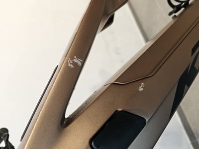 Auf dem bronzefarbenen Fahrradrahmen sind Kratzer und Schrammen sichtbar. Auf dem bronzefarbenen Fahrradrahmen sind Kratzer und Schrammen sichtbar.