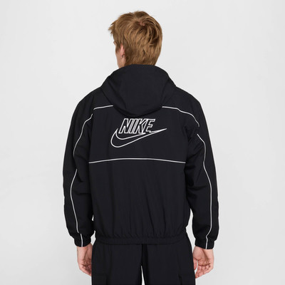 Zadní pohled na muže v černé bundě Nike s bílým logem. Zadní pohled na muže v černé bundě Nike s bílým logem.