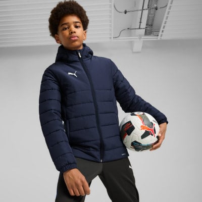 Ein Junge in einer dunklen Kapuzenjacke hält einen Fußball in der Hand. Ein Junge in einer dunklen Kapuzenjacke hält einen Fußball in der Hand.