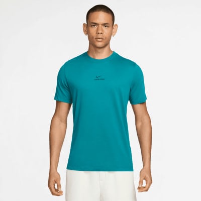 Ein Mann in einem türkisfarbenen Nike Pro T-Shirt und weißer Hose posiert vor weißem Hintergrund. Ein Mann in einem türkisfarbenen Nike Pro T-Shirt und weißer Hose posiert vor weißem Hintergrund.