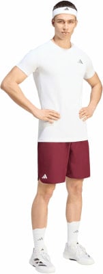 Ein Mann in einem weißen T-Shirt, burgunderfarbenen Shorts und einem weißen Adidas-Stirnband.
