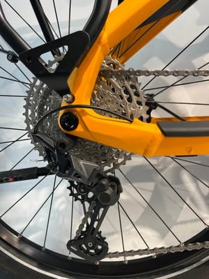 Detail des Schaltwerks und der Kassette eines Mountainbikes mit orangefarbenem Rahmen.