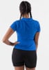 Rückansicht einer Frau in einem blauen Poloshirt und schwarzen Shorts mit Zöpfen.
