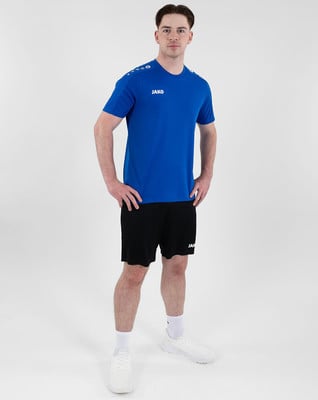 Ein Mann in einem blauen T-Shirt und schwarzen Shorts steht vor einem weißen Hintergrund. Ein Mann in einem blauen T-Shirt und schwarzen Shorts steht vor einem weißen Hintergrund.