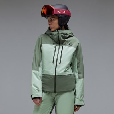 Eine Frau in einer hellgrünen Skijacke und Hose mit Helm.