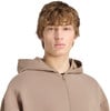 Junger Mann im braunen Hoodie mit Reißverschluss auf weißem Hintergrund.