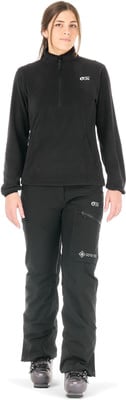 Frau in schwarzem Fleece-Pullover und Skihose mit Skischuhen.