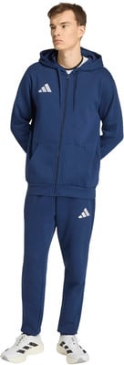 Ein Mann im dunkelblauen Adidas-Anzug mit Logo auf Brust und Bein. Ein Mann im dunkelblauen Adidas-Anzug mit Logo auf Brust und Bein.