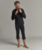 Ein Mann in einem schwarzen Langarmshirt und 3/4-Hose lächelt.
